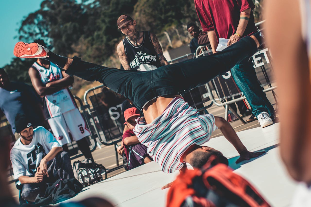 Energetic breakdance move performed outdoors with a lively audience.